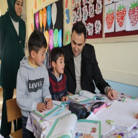 Okumayı öğrenen çocuklarla kitap okudu