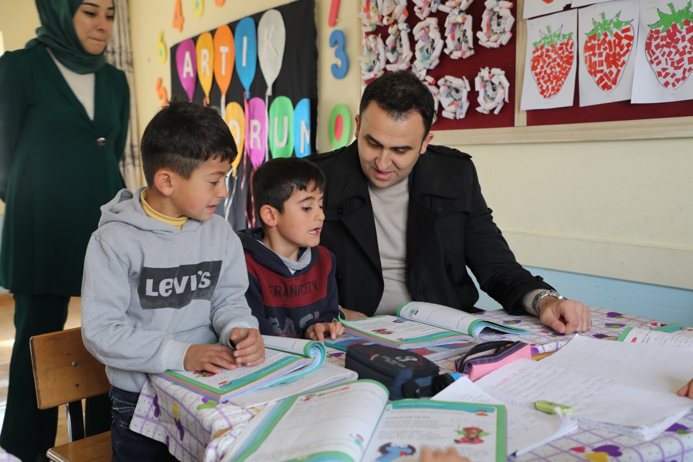 Okumayı öğrenen çocuklarla kitap okudu;
